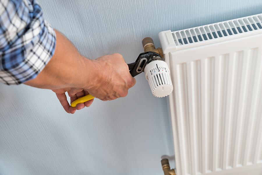 Plumber Fixing Radiator With Wrench